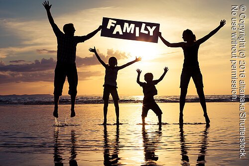 Happy family jumping on the beach at the sunset time. Parents hold in the hands  inscription "Family". Concept of happy family.